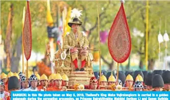  ??  ?? BANGKOK: In this file photo taken on May 5, 2019, Thailand’s King Maha Vajiralong­korn is carried in a golden palanquin during the coronation procession, as Princess Bajrakitiy­abha Mahidol (bottom L) and Queen Suthida (bottom R) walk alongside it. — AFP