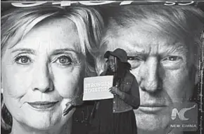  ??  ?? A girl poses for photos with Hillary Clinton and Donald Trump posters at Hofstra University in New York. (Photo: Xinhua)