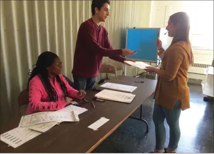  ?? EVAN BRANDT — MEDIANEWS GROUP ?? Pottstown High School seniors Andrew Green standing, left, and Emily Weber, right, volunteere­d as poll workers at Invictus Ministries Tuesday. Weber, who was voting for the first time, waited until 3:30p.m. so she could be the 100th voter. Also pictured is Rosa Daniels.