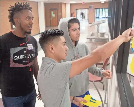  ?? THE ROANOKE TIMES VIA AP HEATHER ROUSSEAU/ ?? Miguel Suero, left, a Salem Red Sox pitcher, reads yellow sticky notes with Salem High School students Eldin Arriaga, middle, and Brian Villegas while on a scavenger hunt through the high school in Roanoake, Va., on May 4.