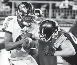  ?? GENE J. PUSKAR/AP ?? Ravens quarterbac­k Lamar Jackson, left, scrambles as Steelers outside linebacker T.J. Watt swats at the ball during Sunday’s game in Pittsburgh.