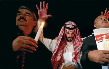  ?? AP ?? An activist, wearing a mask depicting Saudi Crown Prince Mohammed bin Salman, holds up his hands, painted with fake blood as he protests the killing of Saudi journalist Jamal Khashoggi, during a candleligh­t vigil outside Saudi Arabia’s consulate in Istanbul yesterday.