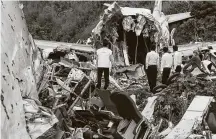  ?? Arunchandr­a Bose / AFP via Getty Images ?? Officials on Saturday inspect the wreckage of an Air India Express plane that went off a runway at the Kozhikode airport.