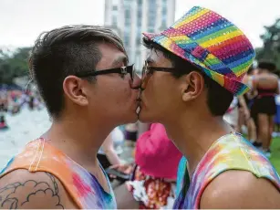  ?? Photos by Yi-Chin Lee / Staff photograph­er ?? Couples such as Jorge Ibarra, above left, and Stefen Rios flocked to the City Hall reflection pool Saturday for the Houston Pride Festival. Nico Morris, left, of Conroe, raises a rainbow flag as thousands gather to celebrate.