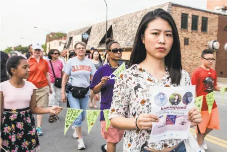 ?? Holly Hart / Champaign (Ill.) News-Gazette ?? Fangqin Wan joins a walk Thursday in Urbana, Ill., to raise awareness of Yingying Zhang, a Chinese scholar who went missing.