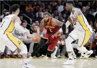  ??  ?? LOS ANGELES: Cleveland Cavaliers’ Kyrie Irving, center, drives past Los Angeles Lakers’ Julius Randle, right, as Lakers’ D’Angelo Russell watches during the second half of an NBA basketball game Sunday, in Los Angeles. The Cavaliers won 125-120. — AP