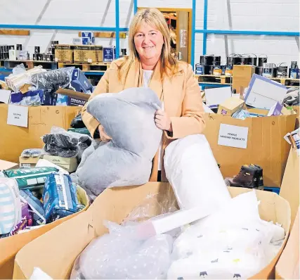  ?? Picture Paul Reid ?? Pauline Buchan, strategic manager of The Cottage Family Centre charity, sifts through items at Amazon’s Lochgelly depot in Fife