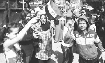  ?? AFP photo ?? Egyptian women and youths dance and celebrate with national flags outside a polling station on the first day of the 2018 presidenti­al elections, in al-Haram neighbourh­ood in the capital Cairo’s southweste­rn Giza district. —