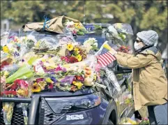  ??  ?? Unspeakabl­e: A mourner leaves flowers on the car belonging to Eric Talley, the Boulder officer and father of seven killed in Sunday’s rampage.