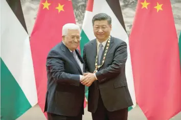  ?? — Reuters ?? Palestinia­n President Mahmoud Abbas shakes hands after presenting a medallion to Chinese President Xi Jinping during a signing ceremony at the Great Hall of the People in Beijing on Tuesday.