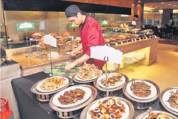  ??  ?? A staff member arranges dipping sauces at the grilling station.