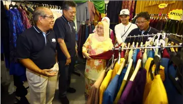  ??  ?? Juma’ani (centre) browses in a clothing stall at Majma Raya Fest. She is accompanie­d by Putit (left), Abang Shibli (second left) and Misnu (right).