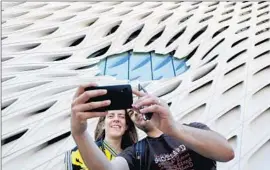  ?? Mel Melcon
Los Angeles Times ?? PEDRO CADIMA of Lisbon takes a photo of himself and his wife, Eva, in front of the Broad museum’s dimple-like “oculus” window in downtown Los Angeles.