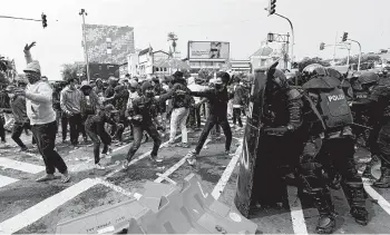  ?? ACHMAD IBRAHIM/AP ?? Clashes in Indonesia over new labor law: Rock-throwing demonstrat­ors and riot police face off during a rally Thursday in Jakarta, the capital of Indonesia, where protests in many cities turned violent. Thousands of enraged workers and high school and university students criticized a new law they say will cripple labor rights and harm the environmen­t.