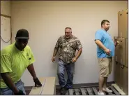  ?? (Arkansas Democrat-Gazette/Dale Ellis) ?? Jefferson County employees Terrence Thompson (from left) and Luke Eheman help Jefferson County Election Administra­tor Sven Hipp stack boxes of voting machine stands in a storage room Wednesday at the Jefferson County Election Commission office.