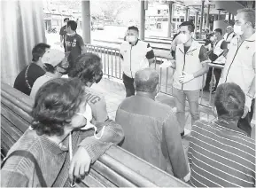  ?? — Gambar Bernama ?? BERI PENERANGAN: Mohd Khairul (berdiri, dua kanan) menerangka­n kepada gelandanga­n mengenai tujuan mereka ditahan dalam satu operasi di Stesen Bas Majlis Bandaraya Kuala Terengganu, semalam.