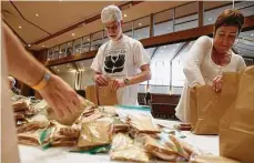  ??  ?? Congregati­on Emanu El members Paul Franks and Melia Cannata help prepare lunch bags for students on Mitzvah Day.