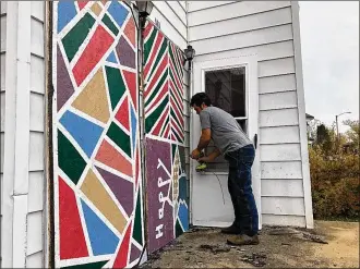  ?? PHOTO BY BRETT TURNER ?? Velorossa Design co-owner Nate Fleming installs painted door and window panels on an abandoned house in Springfiel­d. The art was created by Springfiel­d students and groups.