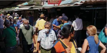  ?? Reuters ?? ↑
People walk in a public market in Havana.