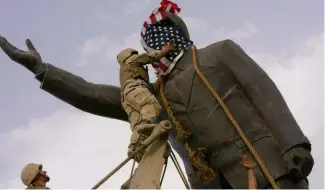 ?? ?? A statue of Saddam Hussein with an American flag before toppling in downtown Baghdad, Iraq, on April 9, 2003. C