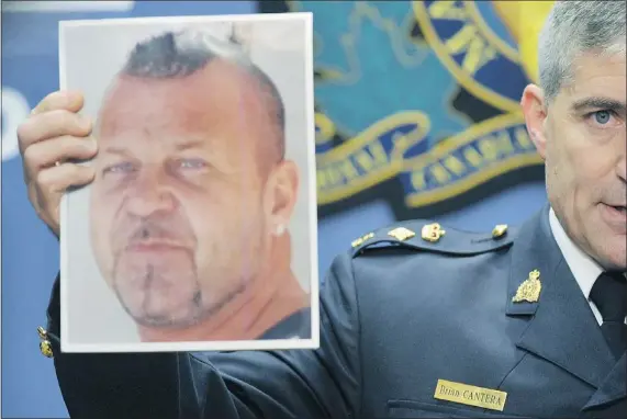  ?? WAYNE LEIDENFROS­T/PNG ?? RCMP Supt. Brian Cantera holds a photo of Hells Angel Brian Oldham, who’s wanted for allegedly traffickin­g in drugs.