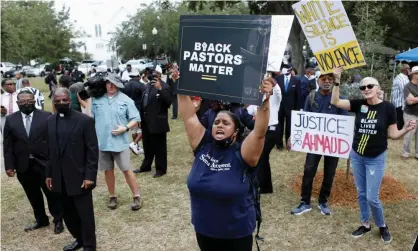  ?? Octavio Jones/Reuters ?? People hold placards as the Rev Al Sharpton and other pastors gather outside the Glynn county courthouse on Thursday. Photograph: