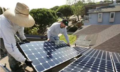  ??  ?? Workers install solar panels on a residentia­l rooftop in Santa Monica, California. Photograph: David McNew/Getty Images