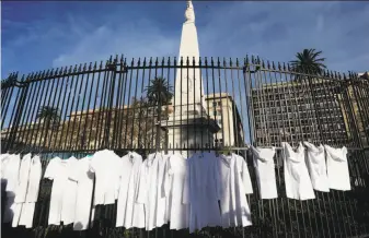  ?? Jorge Saenz / Associated Press ?? In a recent protect, physicians placed their medical coats on an iron gate near a national monument as a symbolic act against efforts to legalize abortion in Buenos Aires.