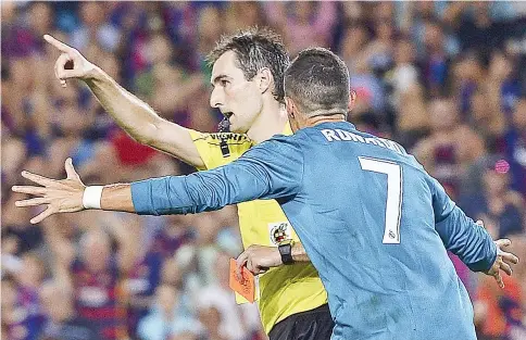  ?? — AFP photo ?? Real Madrid’s Portuguese forward Cristiano Ronaldo (R) gestures after receiving a red card by referee Ricardo de Burgos Bengoetxea during the first leg of the Spanish Supercup football match between FC Barcelona and Real Madrid CF at the Camp Nou...