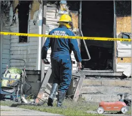  ?? Greg Wohlford The Associated Press ?? Erie Bureau of Fire Inspector Mark Polanski helps investigat­e a fatal fire Sunday. The five children killed in the blaze haven’t been formally identified, but the Erie Fire Department says the dead range in age from 8 months to 7 years.