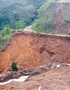  ?? — AFP photo ?? Handout photo courtesy of Michael Dai shows locals standing on a road which was damaged by a landslide near Gumine Station, in the Chimbu Province of Papua New Guinea.