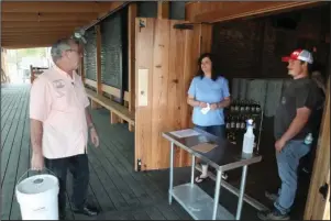  ?? The Sentinel-Record/Richard Rasmussen ?? FOR THE COUNTY: Garland County Treasurer Tim Stockdale, left, talks with co-owner Mary Bradley and employee Marshall Bean after purchasing a 5-gallon container of Crystal Ridge Distillery’s hand sanitizer for the county on Friday.