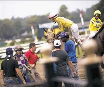  ?? Nathaniel Brooks/The New York Times ?? Jockeys dismount after a race at the Saratoga Race Course earlier this week in Saratoga Springs, N.Y. The open field of contenders for the Travers Stakes is a stark contrast to a year ago, when the arrival of the newly minted Triple Crown champion...