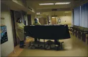  ?? JAE C. HONG — THE ASSOCIATED PRESS FILE ?? Hospital staff members enter an elevator with the body of a COVID-19 victim on a gurney at St. Jude Medical Center in Fullerton in July.