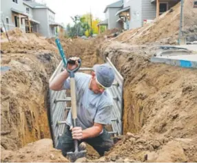  ?? Autumn Parry, Daily Camera file ?? Zack Brown, a plumbing technician, expertly digs around a gas line to put in sewer lines for new duplexes in Lafayette on Oct. 14. Colorado law requires builders, developers and other excavators to call 811 before they dig to ensure they don’t hit gas...