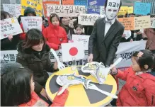  ?? Yonhap ?? Participan­ts stage a performanc­e of eating fish contaminat­ed with radioactiv­e materials during a protest in central Seoul, Wednesday. They urged the government to drop its plan to lift an import ban on fisheries products from Fukushima and eight...