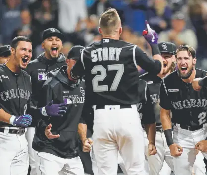  ?? Matthew Stockman, Getty Images ?? Rockies shortstop Trevor Story is met at home plate by his teammates after hitting a two-run walk-off home run in the ninth inning against the Orioles at Coors Field on Friday. It was Story’s second homer of the night.