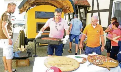  ??  ?? Uwe Nowatzky holt das Spanferkel aus dem mobilen Backofen Marke Eigenbau, beobachtet von Jan Werneburg (links) und Henry Fehr. Auch Pizza wurde im Ofen gebacken. Vierter Mann im Ofenbund ist Arne Harseim. Foto: Jensen Zlotowicz