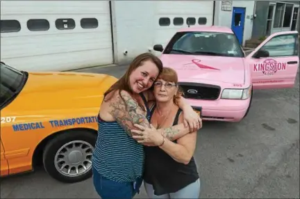  ?? TANIA BARRICKLO — DAILY FREEMAN ?? Kingston Kabs owner Joy Signa, left, hugs her manager, Mary Paschall, on Tuesday. The cab at right has been painted pink as part of a breast cancer awareness effort.