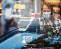  ?? Ting Shen / New York Times file photo ?? A Whole Foods Market employee, wearing a face mask amid the pandemic, runs a cash register in Washington in April.