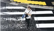  ??  ?? A woman uses her phone while crossing a street in Yamato, Kanagawa Prefecture, Japan, July 1, 2020.