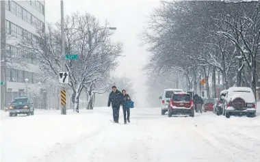  ?? Photos: REUTERS ?? Let it snow: Acouple make their waydown a snow-covered street in Milwaukee, Wisconsin.