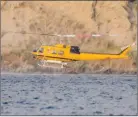  ?? MEGHANN FLETCHER/Special to The Daily Courier ?? A helicopter attached to the Thomas Creek wildfire fills up with water from Skaha Lake as vehicles pass by on Eastside Road over the weekend.