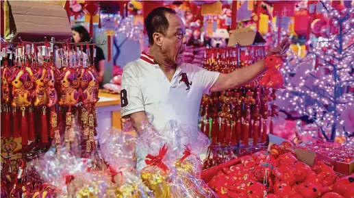  ??  ?? A dog’s year: A customer reacts to decorative dog figurines during the recent festivitie­s. Dog ownership is expected to rise in the Year of the Dog. — AFP