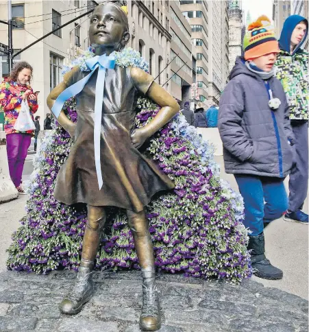  ??  ?? Wall Street’s Fearless Girl statue is draped with a bouquet of flowers to mark Internatio­nal Women’s Day.