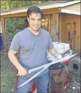  ?? RODNEY HO / RHO@AJC.COM ?? Eric Anthony Leong shows off two of the swords he created that were used on the NBC show “Revolution.”