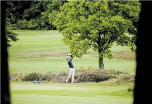  ?? MATT DUNHAM THE ASSOCIATED PRESS ?? A golfer hits a shot on Wednesday after the reopening of a golf club in Sunningdal­e, England.