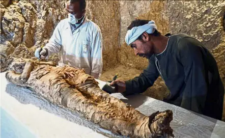  ?? AFP ?? Latest discovery: Egyptian archaeolog­ical technician­s restoring a mummy wrapped in linen found at the newly discovered tomb on the west bank of the Nile River in the Egyptian city of Luxor. —