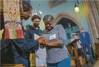  ?? KARL MERTON FERRON/BALTIMORE SUN ?? The Right Rev. Eugene Taylor Sutton, left, Episcopal bishop of Maryland, congratula­tes Darlene Clark as she sheds tears of joy as she, Jermaine Glover, behind, and Amanda Talbot, not pictured, of St. Luke’s Youth Center receive $30,000 on Thursday at the Cathedral of the Incarnatio­n.