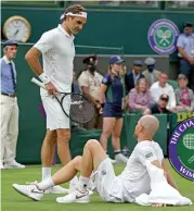  ??  ?? Roger Federer (L) talks to Adrian Mannarino after the latter slipped on the grass during their match. Mannarino later withdrew due to injury